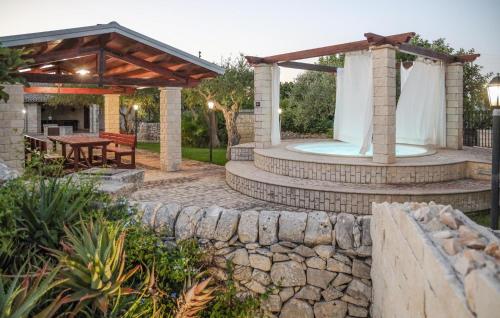 a backyard with a stone wall and a pergola at Lovely Home In Modica in Modica