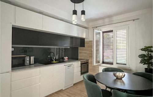 eine Küche mit weißen Schränken und einem Tisch mit Stühlen in der Unterkunft 2 Bedroom Stunning Apartment In Podstrana in Podstrana