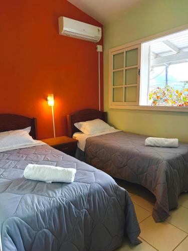 a hotel room with two beds and a window at Pousada Lagoa dos Ventos in Barra de Ibiraquera