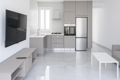 クレンディにあるPenelope Apartments 15の白いキッチン(冷蔵庫、テーブル付)