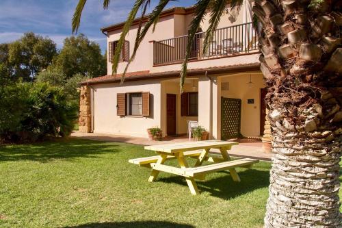 einem Picknicktisch vor einem Haus mit einer Palme in der Unterkunft Residence with swimming pool a few minutes from Alghero in Alghero