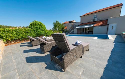 een terras met rieten stoelen naast een zwembad bij Stunning Home In Ugljane in Ugljane
