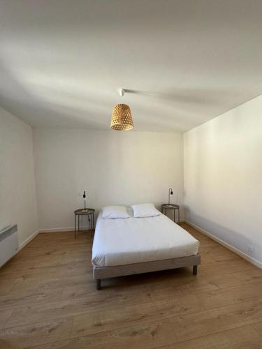 a white bedroom with a bed and two tables at La Petite Maison mitoyenne in Condeissiat