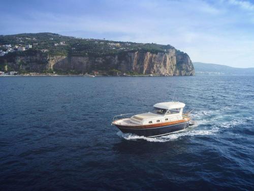 una barca in acqua con una montagna sullo sfondo di Capri Charter a Nerano