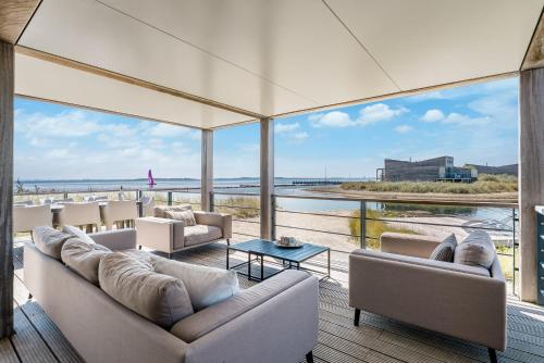 a living room with couches and a view of the ocean at Villa Super VIP | 4 Pers. (Villa 3) met privéstrand in Ouddorp