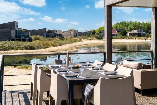 a dining table and chairs on the deck of a boat at Villa Super VIP | 4 Pers. (Villa 3) met privéstrand in Ouddorp