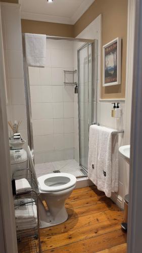 a bathroom with a toilet and a shower with towels at Tintagel Guest House in Cape Town