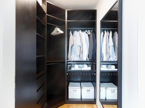 a walk in closet with black cabinets and white clothes at Penthouse Studio with Terrace and City View - 5 mins walk to Hauptbahnhof Train Station in Vienna