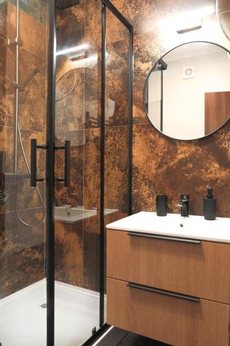 a bathroom with a shower and a sink and a mirror at Green Palm Apartment in Makó