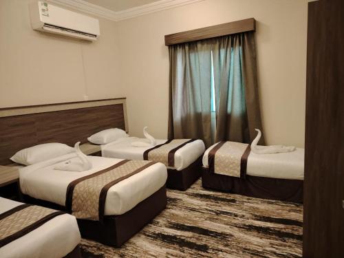 a hotel room with three beds and a window at فندق فجر الرسالة in Al ‘Azīzīyah