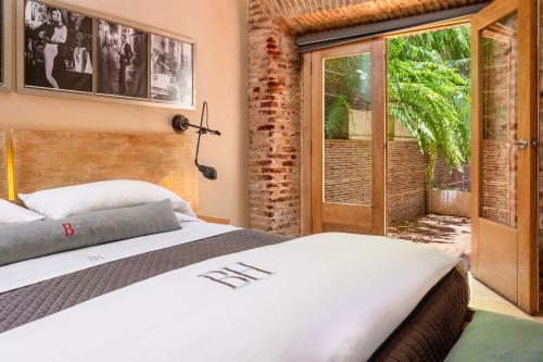 a bedroom with a bed and a sliding glass door at Billini Hotel, Historic Luxury in Santo Domingo