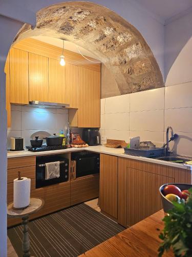 a kitchen with wooden cabinets and a large stone archway at Marina Lounge Home in Ponta Delgada
