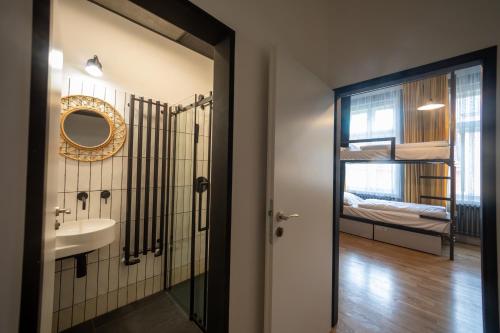 une salle de bain avec un lavabo, un miroir et un lit dans l'établissement Czech Inn, à Prague