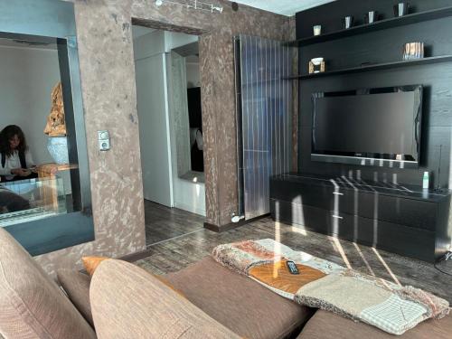 a living room with a couch and a flat screen tv at KOSIS Townhouse mit Spa Zugang im KOSIS Sports Lifestyle Hotel in Fügen