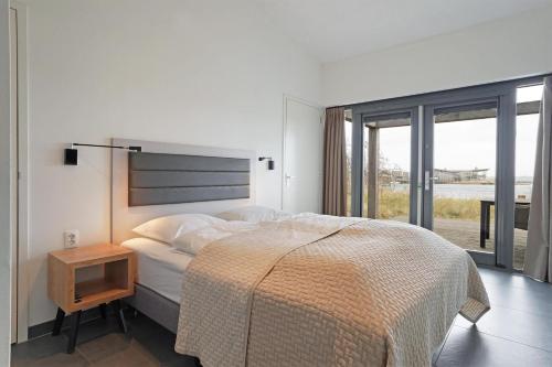 a white bedroom with a bed and a night stand at Seaside Family Villa 6p - Direct bij het Strand - Villa 24 in Ouddorp