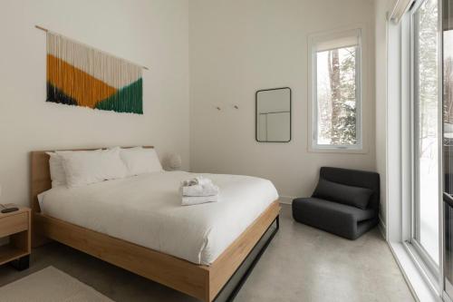 a bedroom with a bed and a chair at Woodland - Terrace - Fire pit - 15min Tremblant in La Conception
