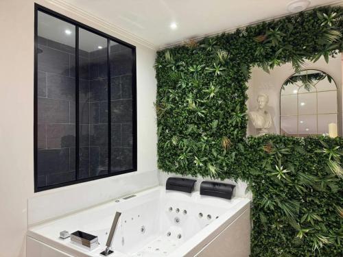 a bathroom with a large green wall with a bath tub at Le Rom'Antik in Noyal-Pontivy