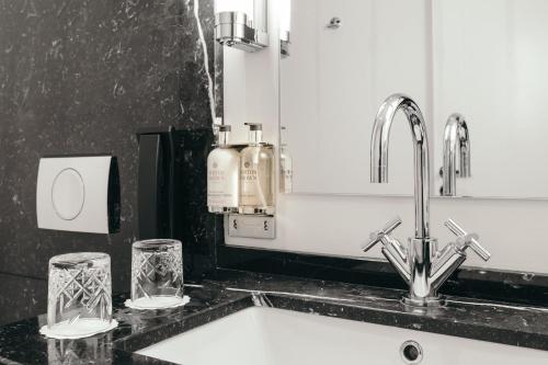 a bathroom sink with two glasses and a mirror at Hotel Borg by Keahotels in Reykjavík