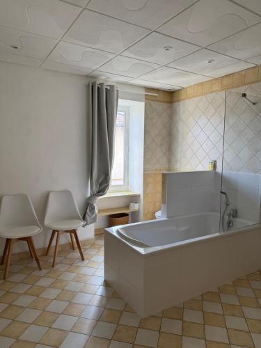 a large bathroom with a tub and two chairs at Le Studio in Condeissiat