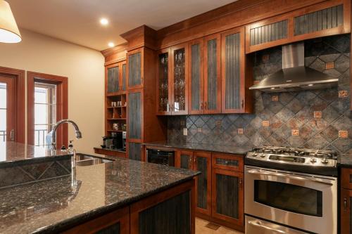 a kitchen with wooden cabinets and a stove top oven at Deluxe Ski in-out - HotTub - Fire - PingPong - View in Mont-Tremblant