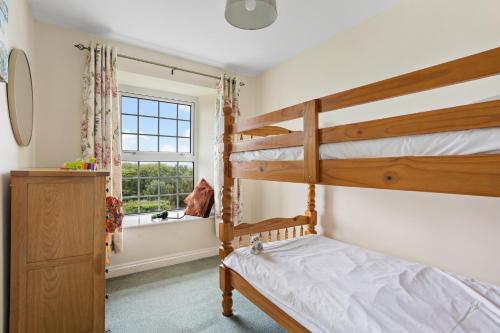 a bedroom with two bunk beds and a window at Rose Cottage in Port Isaac