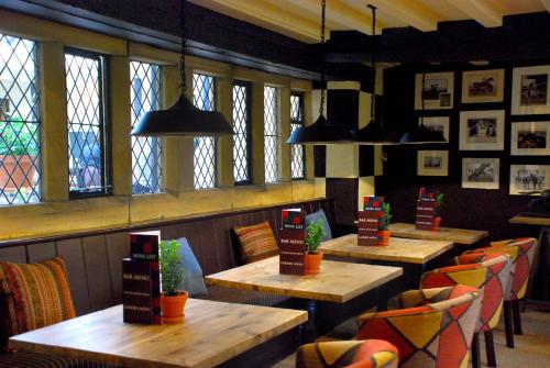 a restaurant with wooden tables and chairs and windows at The Broadway Hotel in Broadway