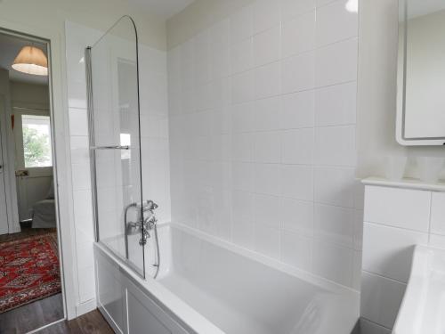 une salle de bain blanche avec une douche avec une porte vitrée dans l'établissement The Dairy, à Glasserton