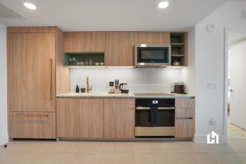 a kitchen with wooden cabinets and a microwave at Stylish Apartments with Partial Ocean Views in Downtown! in Miami