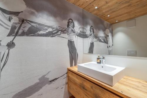ein Badezimmer mit einem Waschbecken und einem Wandgemälde in der Unterkunft BRENTA ALTA ALPINE LODGE MhD in Madonna di Campiglio