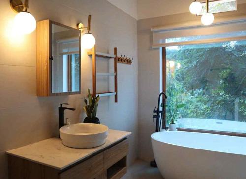a bathroom with a tub and a sink and a window at Villa Đăng HảI in Buôn Du Enguôl