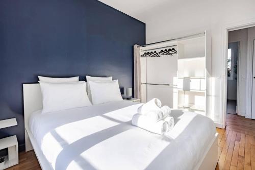 Un dormitorio con una gran cama blanca con una pared azul. en Élégance & confort - aux portes de Paris, en Aulnay-sous-Bois
