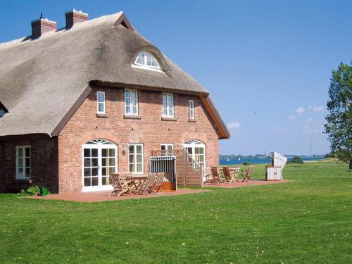 a large brick house with a thatched roof at Ferienwohnung "Wildgans" in Schaprode