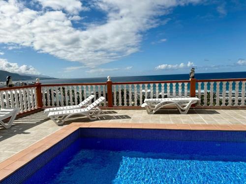 een balkon met een zwembad en stoelen en de oceaan bij Sunrise Serenity in Puerto de la Cruz in Puerto de la Cruz