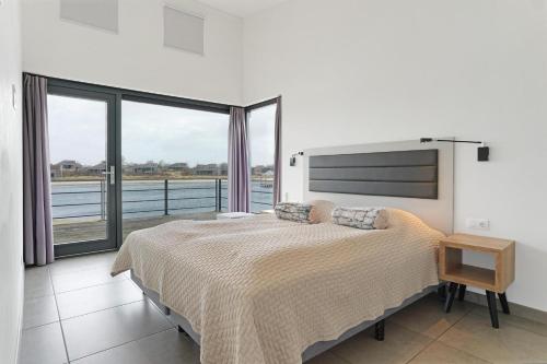 a bedroom with a large bed and a large window at Grevelingenmeer Panorama Villa 4p - Luxe & Natuur - Villa 14 in Ouddorp