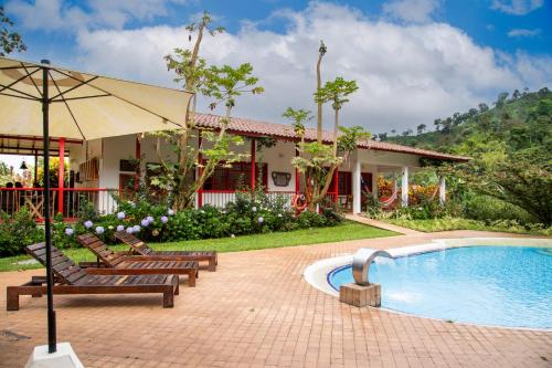 a resort with a pool and chairs and an umbrella at Hacienda Venecia Coffee Farm Hotel in Manizales