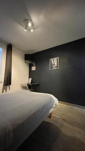een slaapkamer met een bed en een zwarte muur bij LES VOYAGEURS - Vairé in Vairé