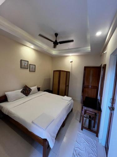 une chambre avec un grand lit blanc et une chaise dans l'établissement Tha Villa Calangute, à Calangute
