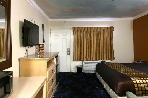 a hotel room with a bed and a television at Robinhood Motel Anaheim West in Anaheim
