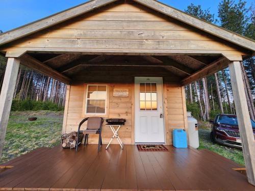 a cabin with a wooden deck with a white door at Off-Grid Cabin Nestled Among Nature with Lovely Landscape Views in Maine in Lavertue