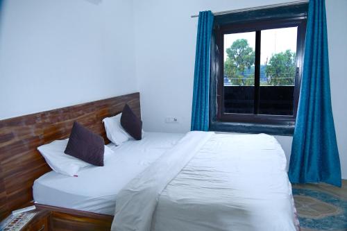 une chambre avec un grand lit avec une fenêtre dans l'établissement Namami Atithi Grah, à Barsāna