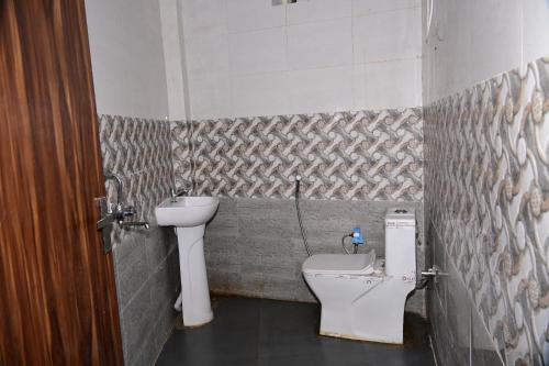 une salle de bain avec un lavabo et des toilettes dans l'établissement Namami Atithi Grah, à Barsāna