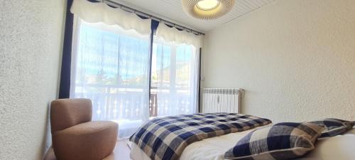 une chambre avec une fenêtre, un lit et une chaise dans l'établissement Eperon 1 NA2 - 3P4, à Les Deux Alpes
