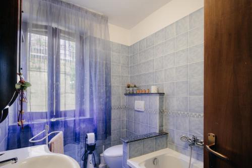 a blue tiled bathroom with a toilet and a sink at Le Margherite in Castiglione del Lago