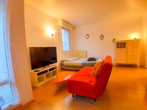 uma sala de estar com uma cadeira vermelha e uma televisão em Grand T1 proche RER A, Vrai lit, Cuisine séparée, RDC em Sartrouville