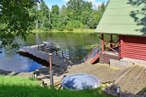a dock with a house and a boat on a lake at LAKE VIEW Resort - Sodyba in Skirlėnai