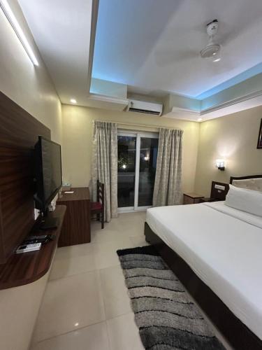 a bedroom with a bed and a flat screen tv at Casa goa in Calangute