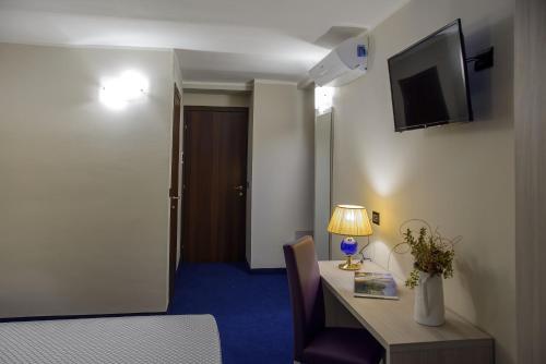 um quarto com uma secretária com um candeeiro e uma televisão em Hotel Torino Porta Susa em Turim