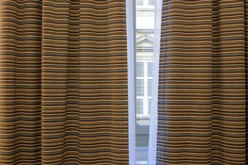 a view of a window from between two curtains at Hotel Torino Porta Susa in Turin