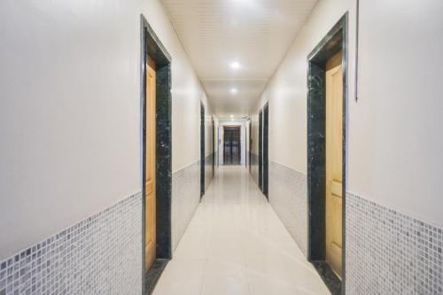 an empty corridor of a hallway with white walls and doors at Hotel O Atithi Lodge in Wagholi
