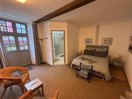 Un dormitorio con una cama y una silla y una ventana. en Au Pied du Chateau, en Brantome en Perigord